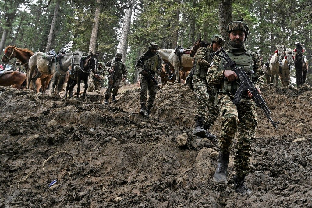 Indian soldiers with guns walking along a dirt path in Baisaran meadow during a search operation in the aftermath of an attack in Pahalgam