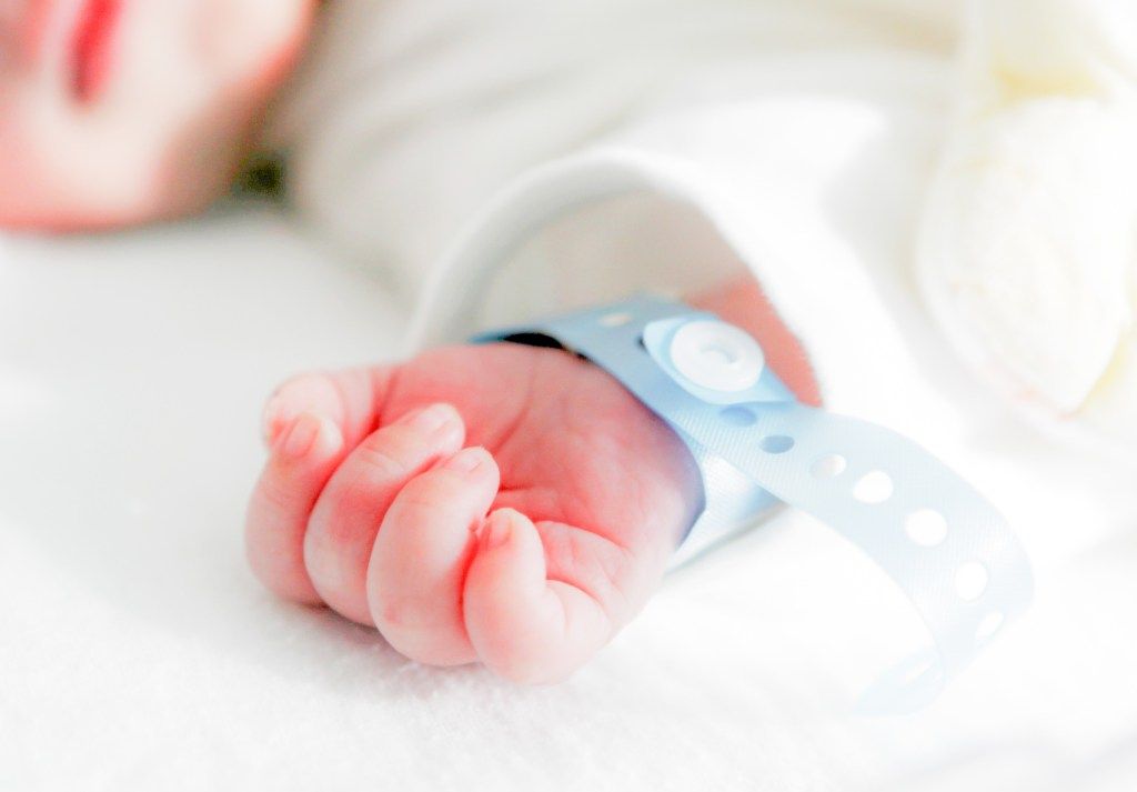 Close-up of a newborn's hand with a hospital identification band.