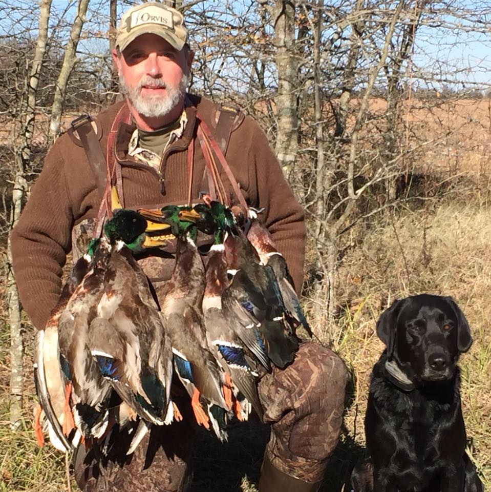 Hunter with a string of ducks and a black lab.