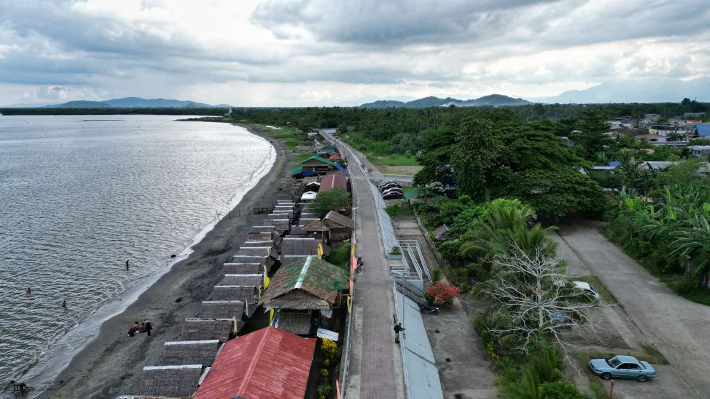 Aerial view of cabanas and restaurants along a beach and a seawall in Palo municipality, Leyte province, Philippines.