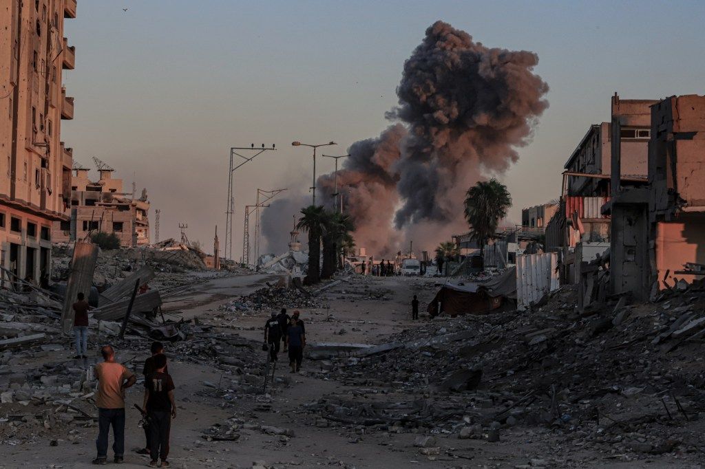 Smoke from an Israeli airstrike rises above damaged buildings in Gaza
</p>
<p><a class=