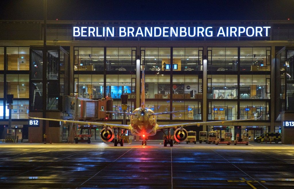 An easyJet airplane parked at Terminal 1 of Berlin Brandenburg Airport at night.