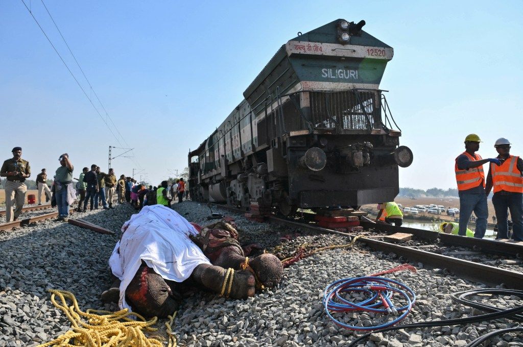 The carcass of an elephant on the railway tracks next to a train and people in Hojai, Assam, after a train accident.