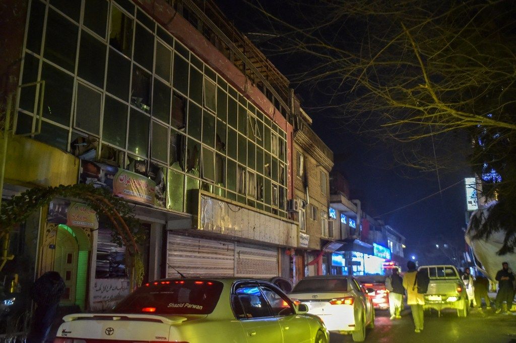 Motorists pass a building with shattered glass windows at night in Kabul after an explosion.