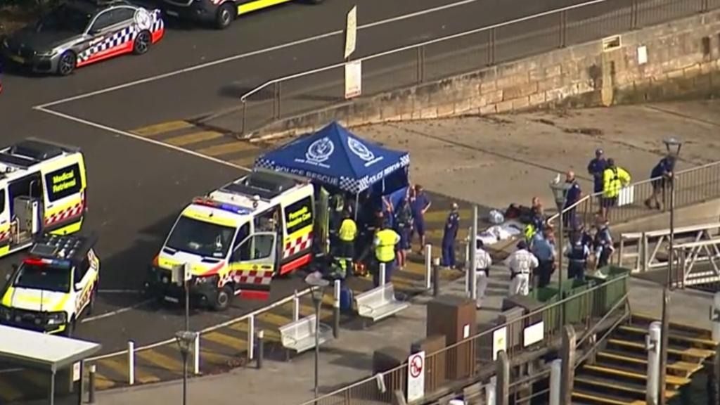 Emergency services on a dock with a medical tent, ambulances, and police vehicles.