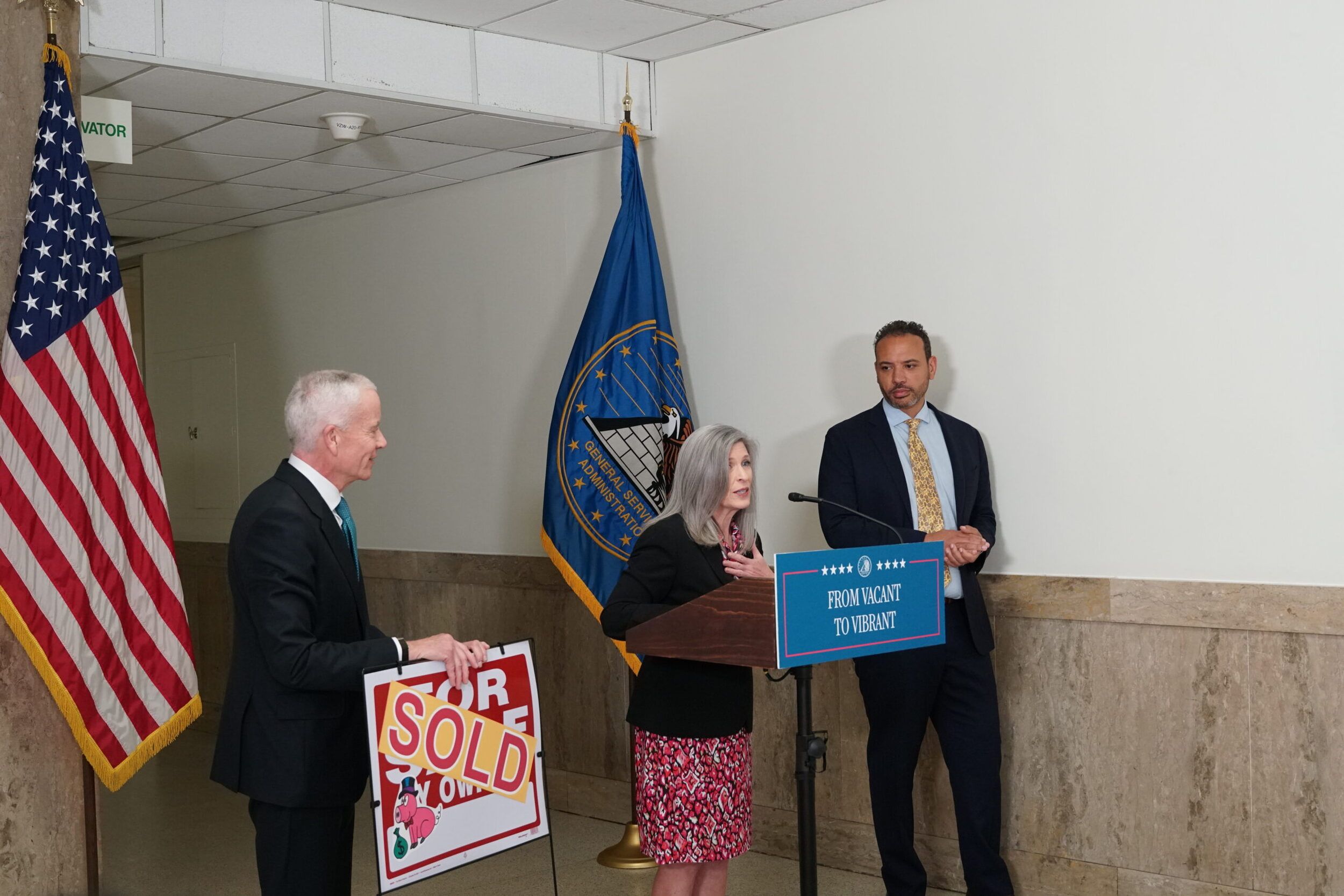 Sen. Ernst, Eric Mulata of Dalian Development, and GSA Administrator Edward C. Forst stand with "sold" sign.