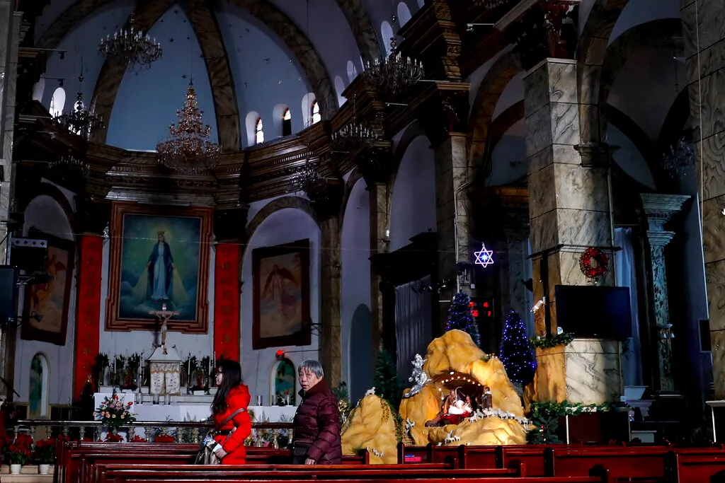 Chinese women walk among pews in a Catholic Church