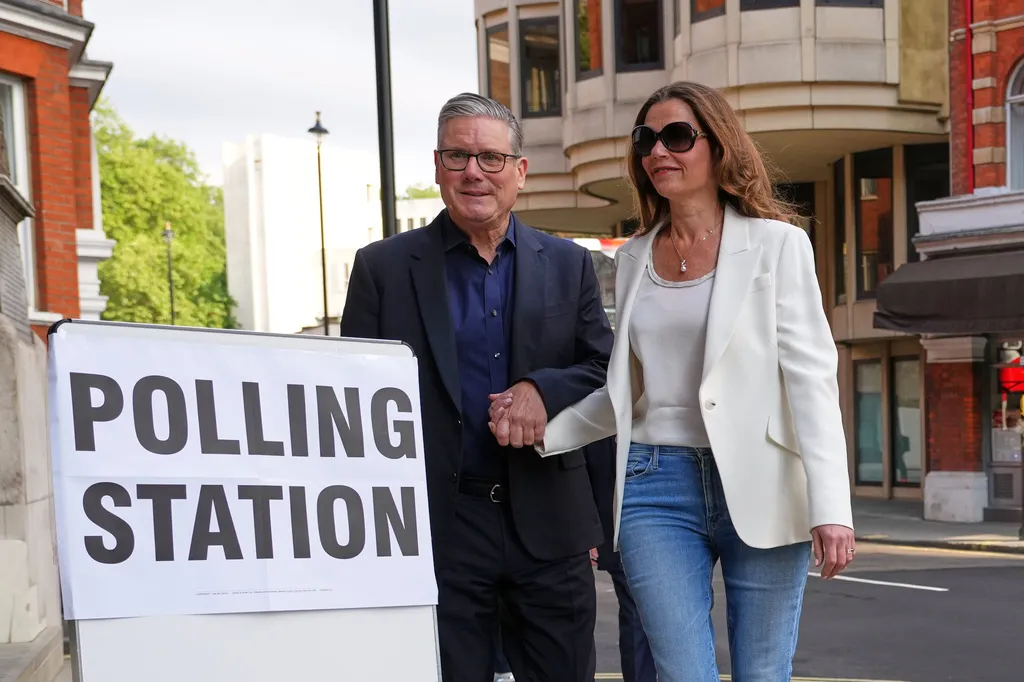 Keir Starmer walks with his wife next to a sign for a polling station