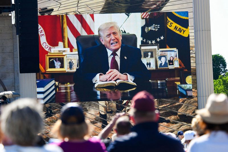 Attendees watch a pre-recorded video of US President Donald Trump reading from the Bible during "Rededicate 250: A National Jubilee of Prayer, Praise and Thanksgiving" on the National Mall in Washington, DC, on May 17, 2026. (Photo by Matthew Hatcher / AFP via Getty Images)