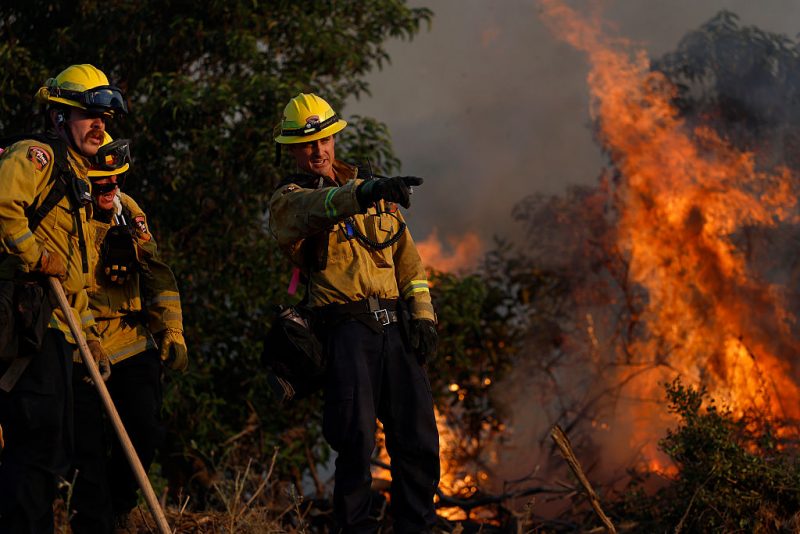 SIMI VALLEY, CALIFORNIA - MAY 18: Cal Fire firefighters battle the Sandy Fire as it burns through heavy brush on May 18, 2026 in Simi Valley, California. The fast-moving Sandy Fire burned more than 1,300 acres near Simi Valley and prompted mandatory evacuation orders as strong winds pushed flames toward homes and nearby communities. The fire has destroyed one home. (Photo by Justin Sullivan/Getty Images)