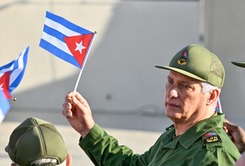 Cuba's President Miguel Diaz-Canel holds a Cuban flag during a rally in support of former Cuban president Raul Castro, 94, who has been indicted by a US court, outside the US Embassy in Havana on May 22, 2026. (Photo by ADALBERTO ROQUE / AFP via Getty Images)