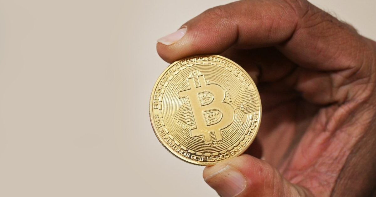 A hand holding a physical Bitcoin token for an institutional demand story.