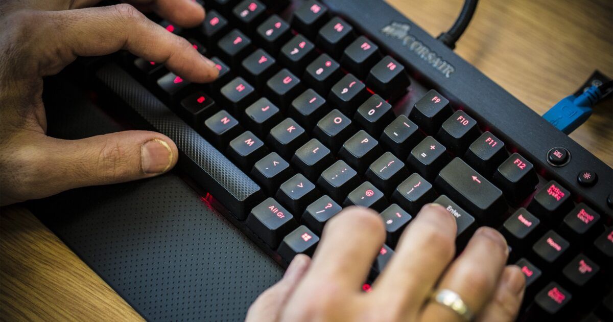 Hands operating a computer keyboard for a crypto private-key breach story.