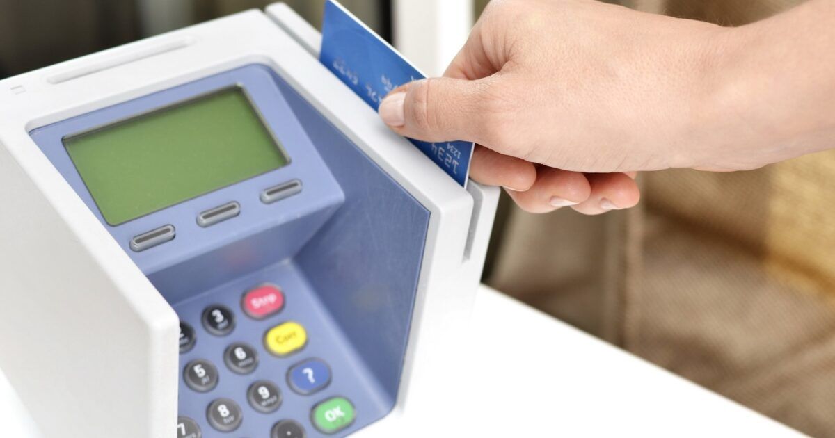 A hand sliding a payment card through a point-of-sale terminal for a stablecoin payments platform story.