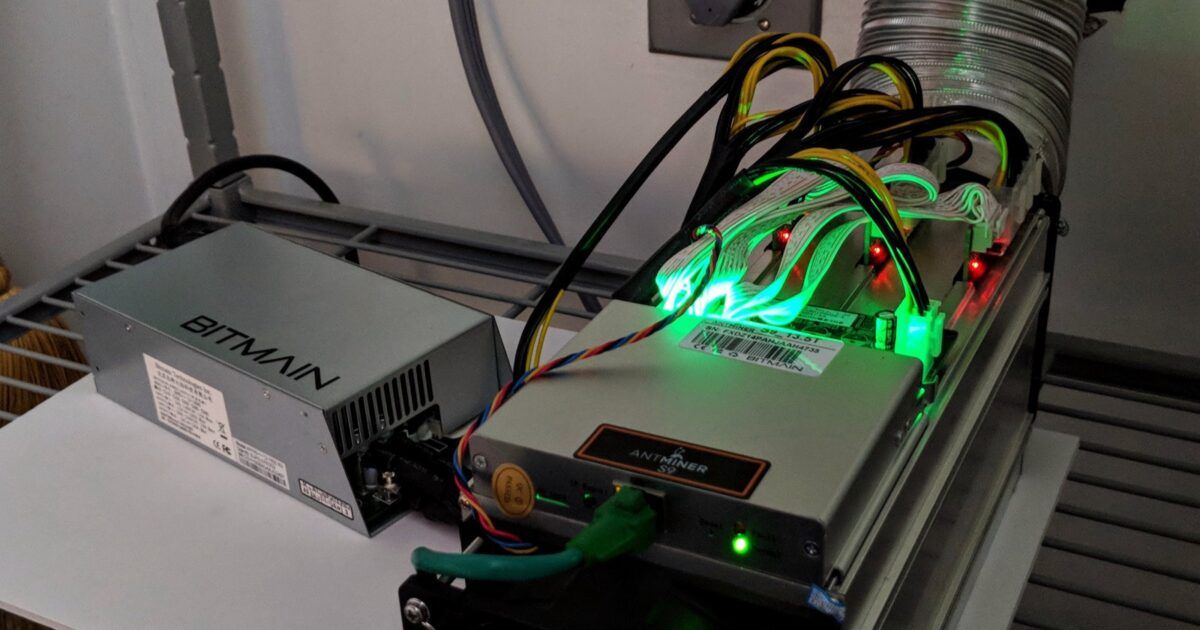 Antminer S9 Bitcoin mining machine running beside its power supply.