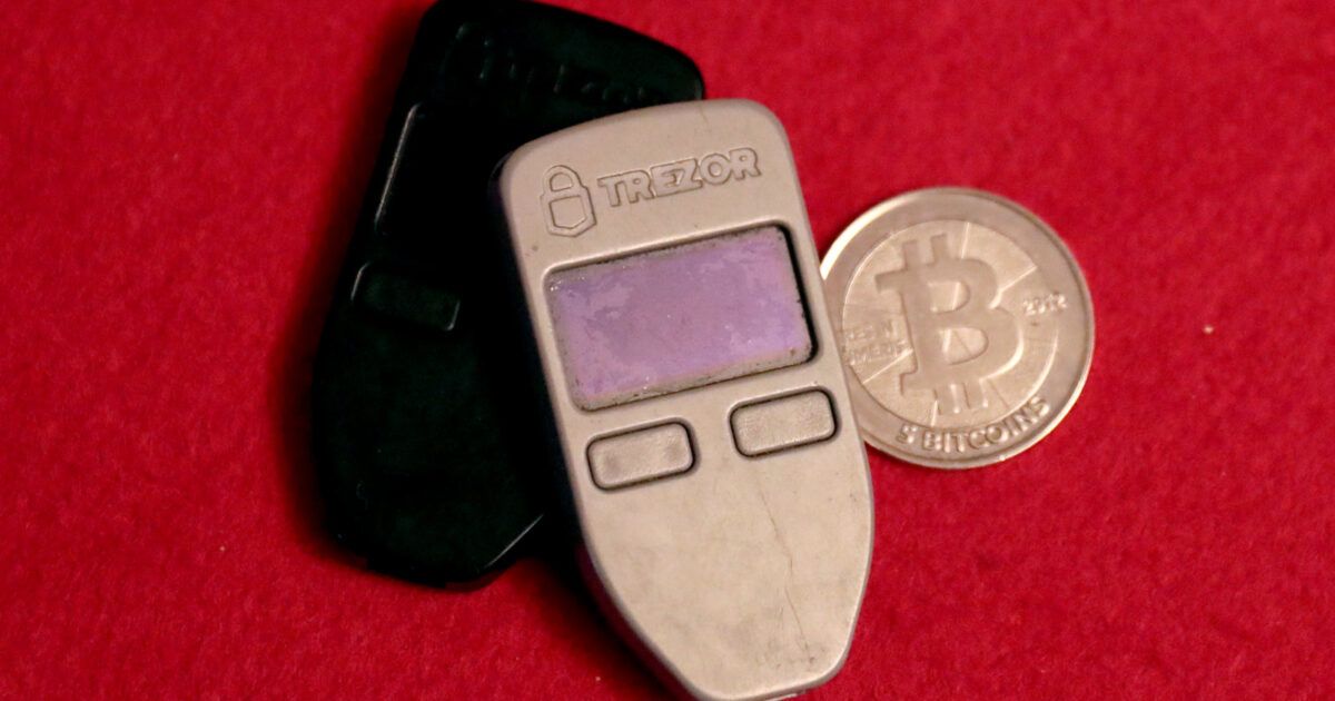 Two Trezor hardware wallets beside a Casascius physical Bitcoin coin.