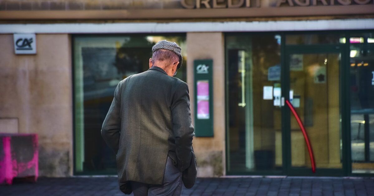 Person walking toward a Credit Agricole branch for a ProCoinNews article about the EURXT euro stablecoin launch.