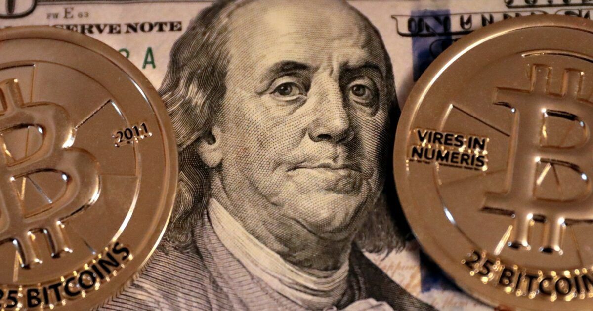 Two physical Bitcoin coins framing Benjamin Franklin on a U.S. 100 dollar bill