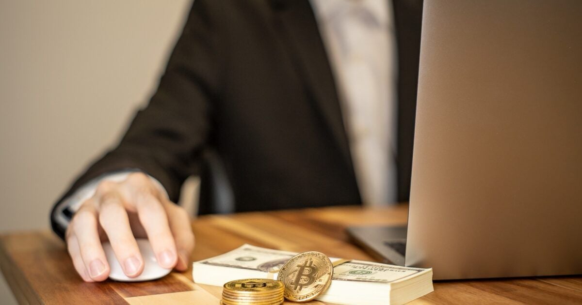 Bitcoin medallions and cash beside an investment laptop