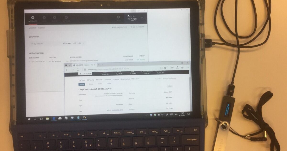 A Ledger hardware wallet beside a laptop showing an actual Bitcoin transfer