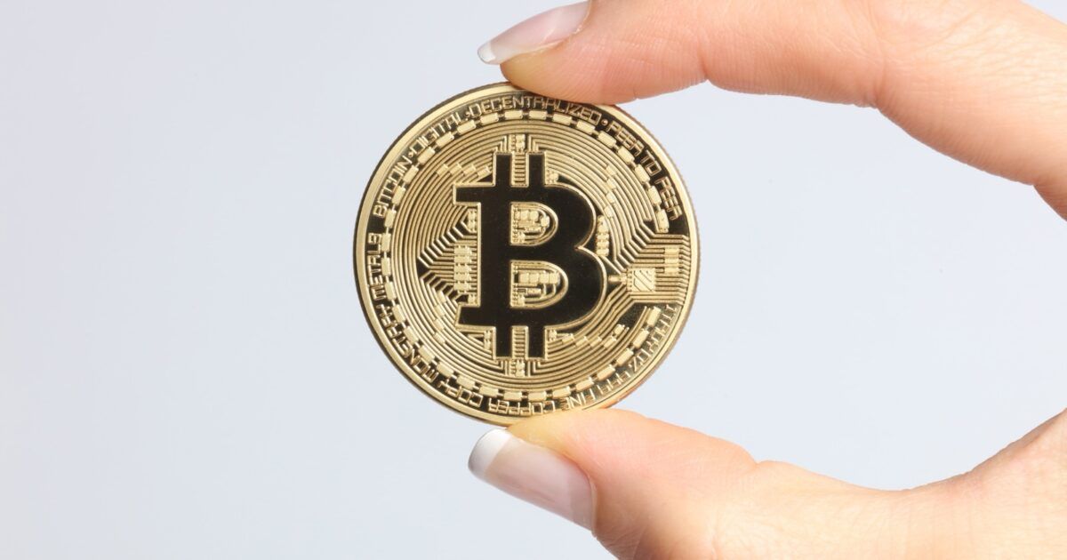 A physical Bitcoin held in a hand, illustrating Strive’s 1,800 BTC purchase