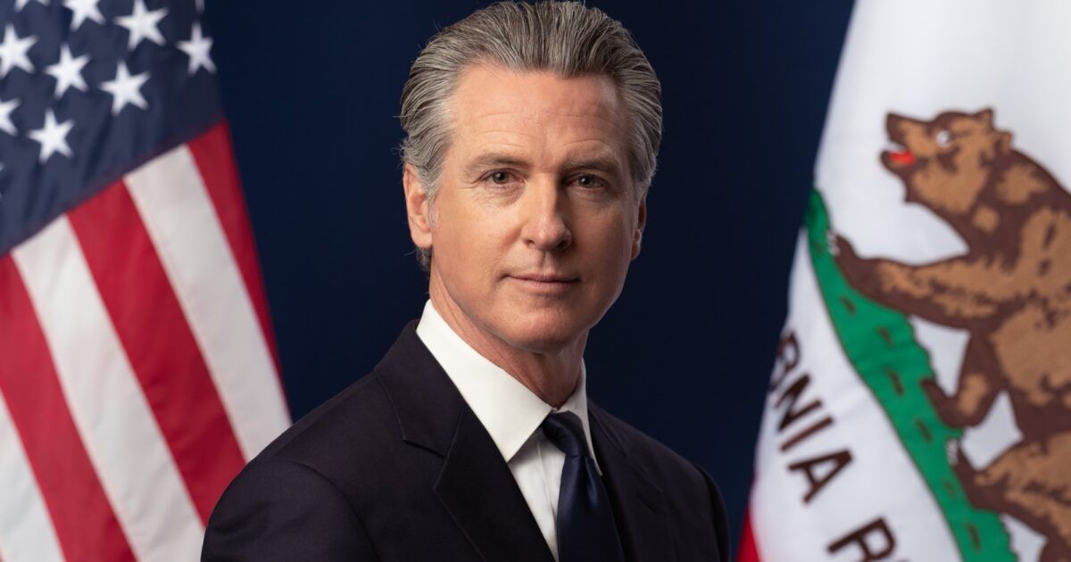 Official portrait of California Governor Gavin Newsom between the United States and California flags