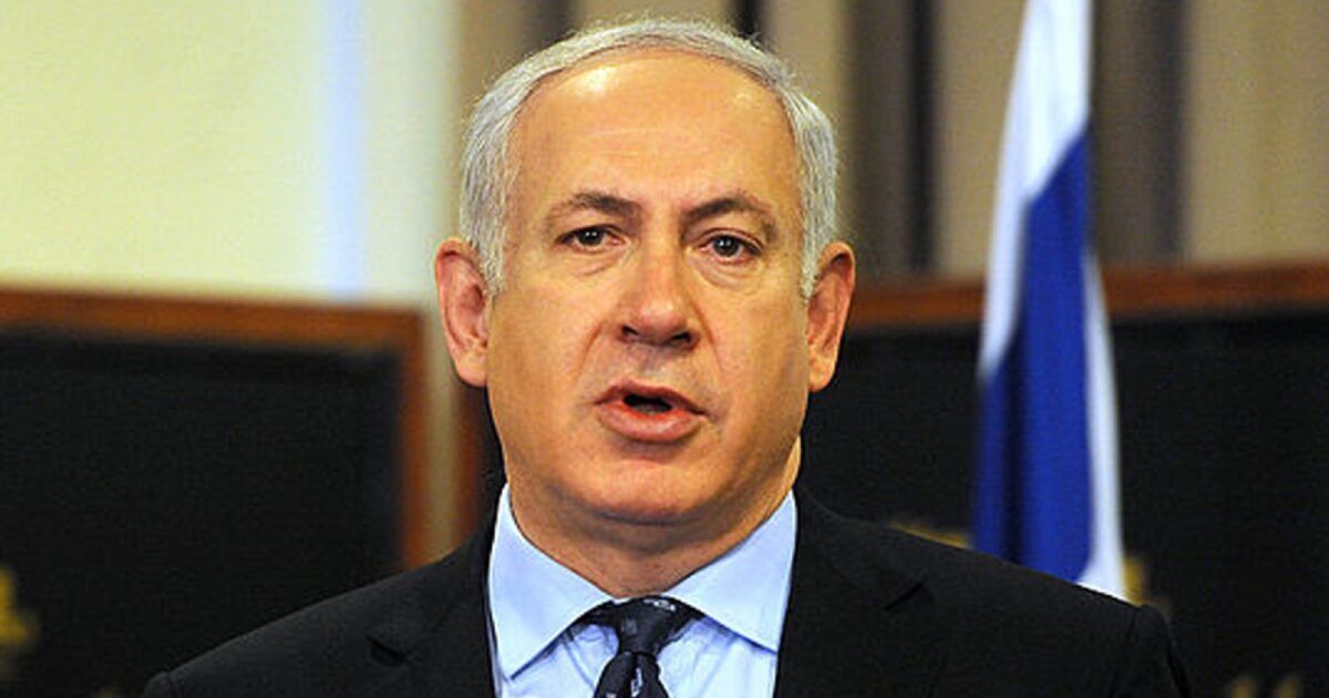 Benjamin Netanyahu speaking with an Israeli flag behind him